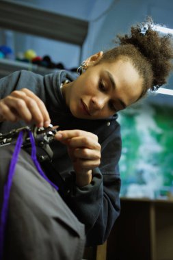 Afrikalı Amerikalı bir zanaatkar halı çekme makinesiyle ipliği dolduruyor. 