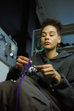 Afrikalı Amerikalı bir zanaatkar ipliği halı çekme silahıyla dolduruyor.