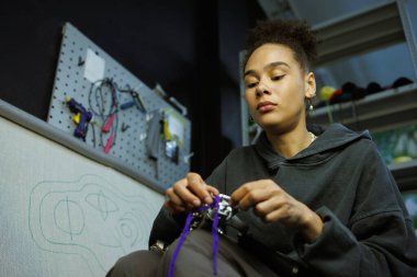 Afrikalı Amerikalı bir zanaatkar ipliği halı çekme silahıyla dolduruyor.