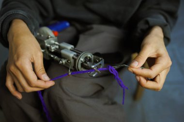 Zanaatkar kadının ipliği halı çekme silahıyla doldurduğu yeri kapatın. 