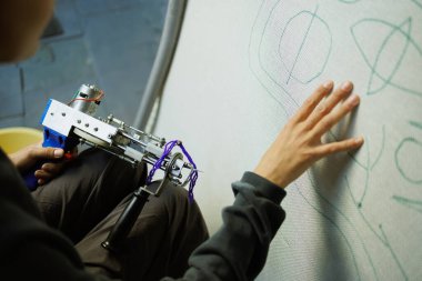 Kumaşın yanında halı çekme tabancası tutan bir kadın.