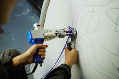 Sanatçının bir parçası, tuvalde desenli halı yapıyor.