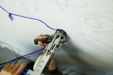 Kısmi kadın poşedi makinesiyle halı yaparken. 