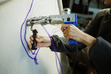 Halı ütüleyen tabancayla halı yapan bir kadın. 