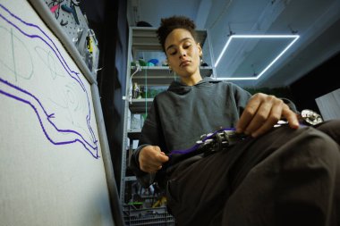 Afrikalı Amerikalı zanaatkar elinde iplik ve halı çekme tabancasıyla tuvalin yanında. 