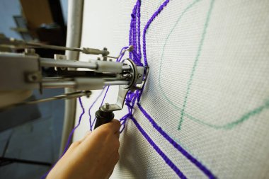 Part of craftswoman making carpet with tufting machine
