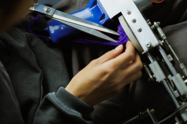 Zanaatkar kadın halı dokuma işi için iplik kesiyor.