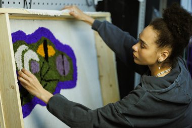 Afrikalı Amerikalı bir zanaatkar çerçeveyi tuvalde tutuyor. 