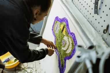 Afrikalı Amerikalı zanaatkar el yapımı halıdaki iplikleri kontrol ediyor.