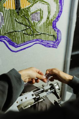 Halı çekme makinesinden iplik çeken bir kadın.