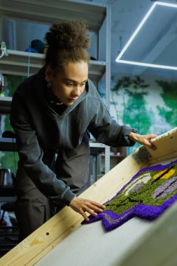 Afrikalı Amerikalı zanaatkar atölyedeki el yapımı halıyı kontrol ediyor.