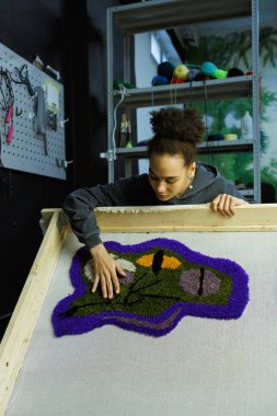 Afrikalı Amerikalı zanaatkar kadın çerçevede el yapımı halı tutuyor.