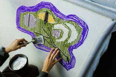 El yapımı halı ipliklerini yapıştırıcı ile onaran bir kadın parçası.