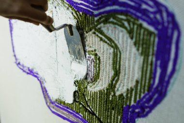 El yapımı halıya yapıştırıcı süren malalı bir kadın. 