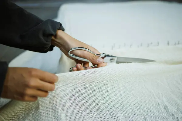 Halı bezi kesen bir zanaatkarın kısmi resmi. 