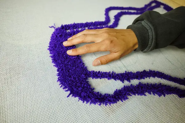 Halı örerken iplikleri kontrol eden bir kadın. 