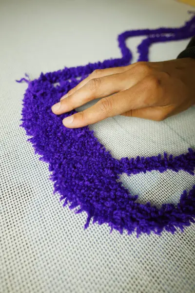 Kumaş ipliğini kontrol ederken halı yapan zanaatkar kadını kapatın.