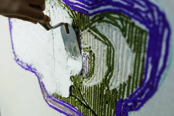 El yapımı halıya yapıştırıcı süren malalı bir kadın. 