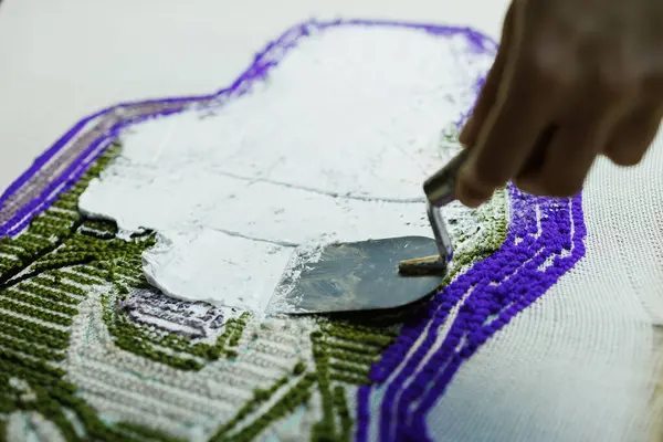 El yapımı halıya yapıştırıcı süren usta kadına yakın çekim.