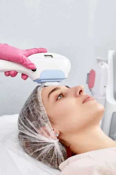 procedure of photoepilation in the beauty salon. Young Woman Receiving Epilation Laser Treatment On Face At Beauty Center Close Up.