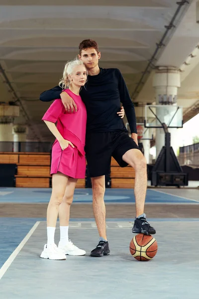 Diversity man and woman playing basketball, posing for camera on city basketball court, lifestyle active leisure young people