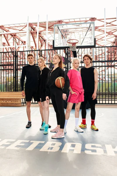 A friendly company of guys and girls are having fun on the basketball court, they are going to play basketball