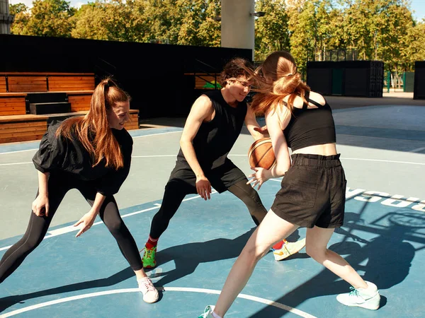 A friendly company of guys and girls are having fun on the basketball court, they are going to play basketball
