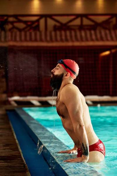 一个戴着帽子和护目镜的游泳者从游泳池里冒出水来 游泳运动员为健康或健康目的而进行的训练 训练或锻炼 — 图库照片