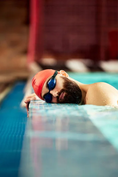 这位游泳运动员把头靠在游泳池边 在训练间歇时把头靠在游泳池边休息 — 图库照片