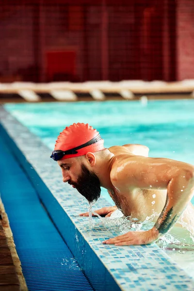 一名职业游泳运动员从游泳池里出来 看着镜头 泳池边游泳运动员的画像 — 图库照片