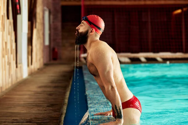 プロの水泳選手がプールから現れカメラを見る プールサイドの水泳選手の肖像 — ストック写真