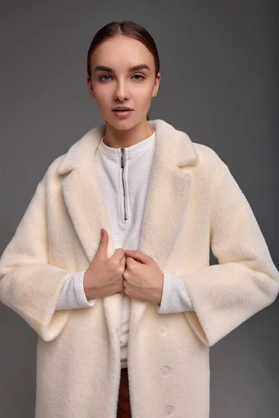 stock image Fashion young woman in a faux fur coat on a gray background