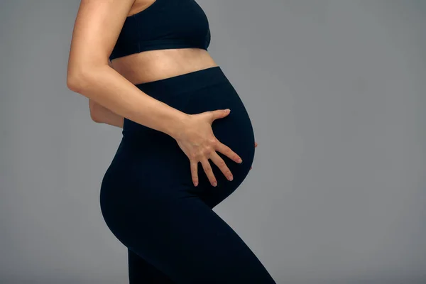 灰色で隔離された可愛い妊娠中の腹 腹部を手で抱きしめる若妻の横顔 妊娠の終わりの第三学期に大きな腹 妊娠生活の概念 — ストック写真