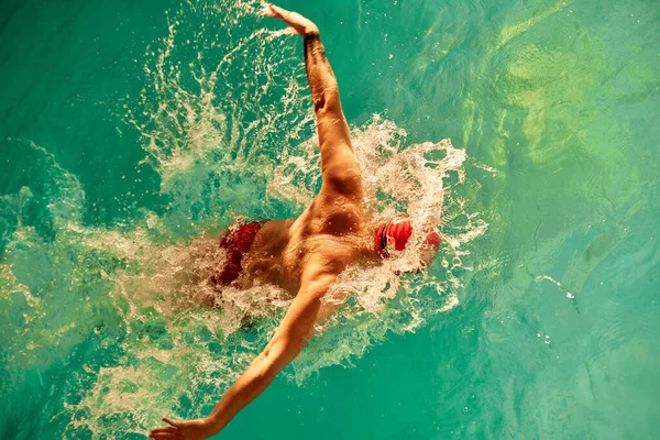 Kırmızı Şapkalı Bir Adam Havuzda Yüzüyor Güneş Işınları Arasında Gözlük — Stok fotoğraf