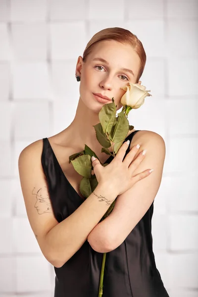 Beautiful young with special needs woman with flowers in her hand holding a flower, woman in black dress. Diversity women with disability and flowers