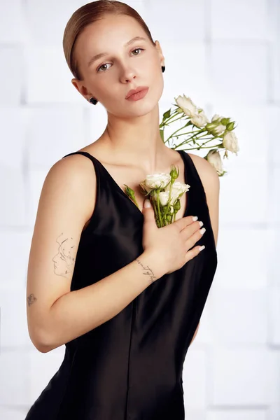 Beautiful young with special needs woman with flowers in her hand holding a flower, woman in black dress. Diversity women with disability and flowers