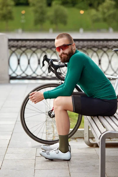 一个骑自行车的人坐在城市公园的长椅上休息 骑自行车时康复 骑自行车是一种业余爱好 — 图库照片