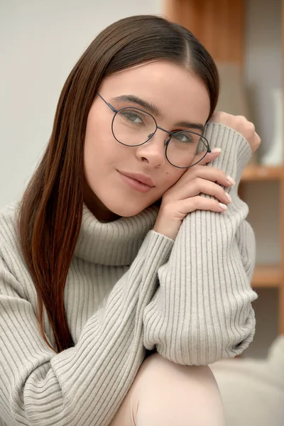 Portrait of a young calm woman in glasses looking through glasses at the camera, shot of a young business woman in glasses, stylish glasses fashion accessory.