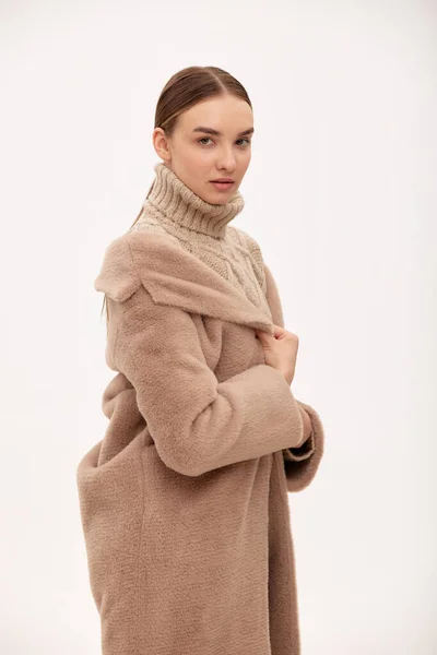 ベージュのフェイクファーのコートでファッショナブルな自信の女の子 フェイクファーで作られた毛皮のコートのための現代的なファッショントレンド 背景にベージュのファーコートに身を包んだモデル — ストック写真