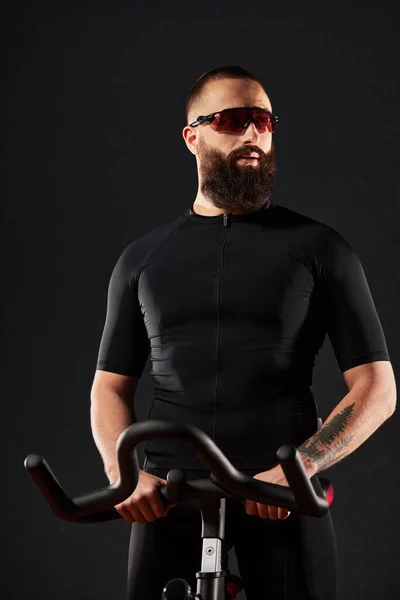 一个在健身房里用自行车锻炼的年轻人 一个带着胡子和眼镜的男人在锻炼自行车上锻炼 健身男子使用航空自行车在交叉健身馆进行有氧运动训练 — 图库照片