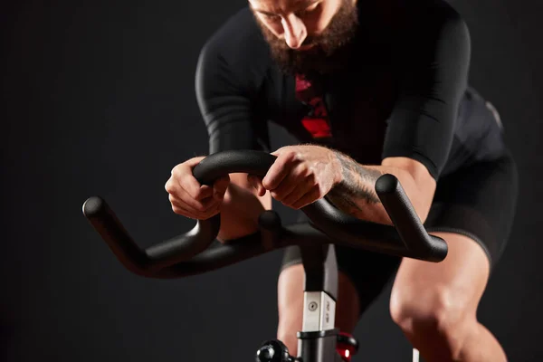 Portrait of a man on an exercise bike in the gym, a man with a beard and glasses on an exercise bike. Fitness man using exercise bike during cardio workout in crossfit gym