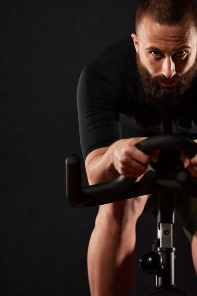 一个男人在健身房里骑跑车 一个男人带着胡子和眼镜在跑车上的画像 健身男子在交叉健身馆进行有氧运动时使用运动自行车 — 图库照片