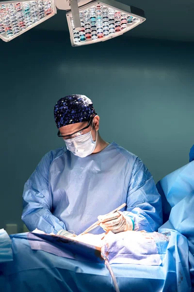 手术室里一名男性外科医生的画像 背景是现代外科和照明设备 一个现代手术室 一名医生的刻苦工作 — 图库照片