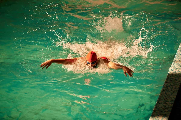 男子游泳者游泳蛙泳 男子戴着红色泳帽和游泳护目镜在游泳池游泳时的近照 — 图库照片