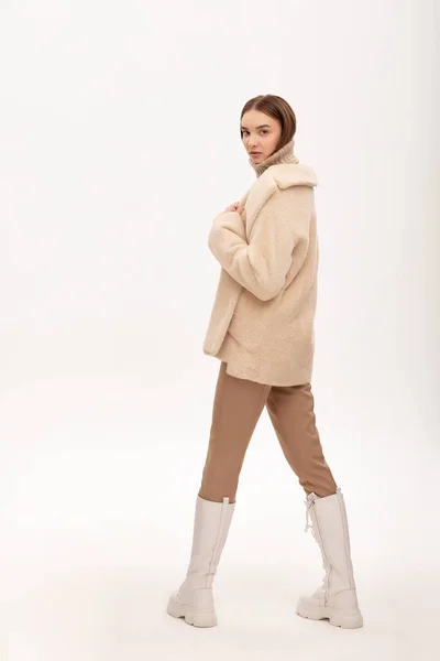 光の背景に毛皮のコートを着た美しいビジネス女性 市場のための写真 製品のデモンストレーション 人工毛皮 人工毛皮で作られた毛皮のコートに身を包んだ女の子 — ストック写真