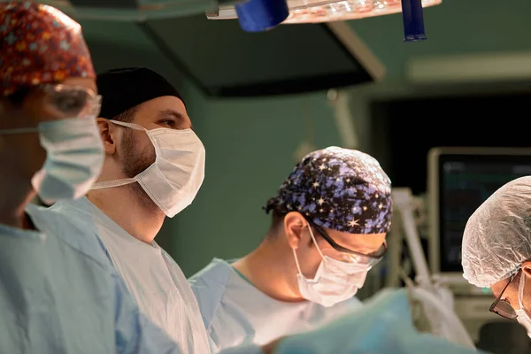 戴口罩的医生们的脸是一个宏伟的计划 一个手术室 一个外科医生在一个有生命保障装置和灯的现代手术室里做手术 挽救生命 癌症就是 — 图库照片