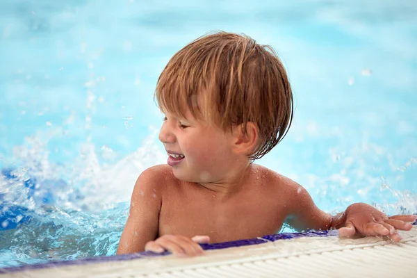 파크의 수영장에서 기쁨에 아이는 수영장의 배경에 카메라를 기쁘게 포즈를 취한다 — 스톡 사진