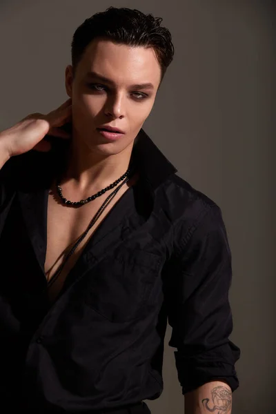 一个穿着黑色衬衫 脖子上戴着珠子的少年黑发男孩的工作室肖像 短短的时髦发型 优雅的性感风格 灰色背景 — 图库照片
