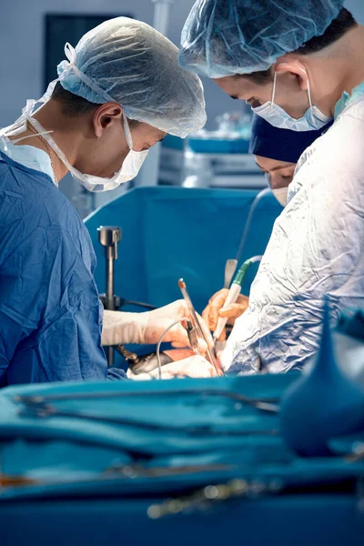 手术室里的一组外科医生弯着腰为病人做手术 复杂的外科手术 高科技的药物 挽救生命 — 图库照片