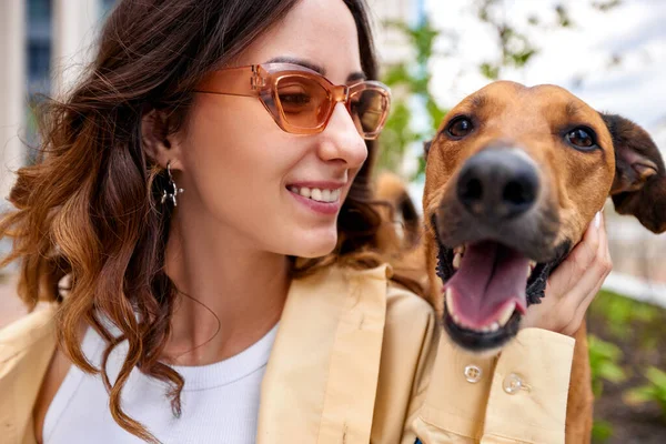 Charming young smiling girl with a golden dog on a walk on a sunny day. The dogs head on the girls shoulder. Love and affection between owner and pet. Adopting a pet from a shelter. Close-up